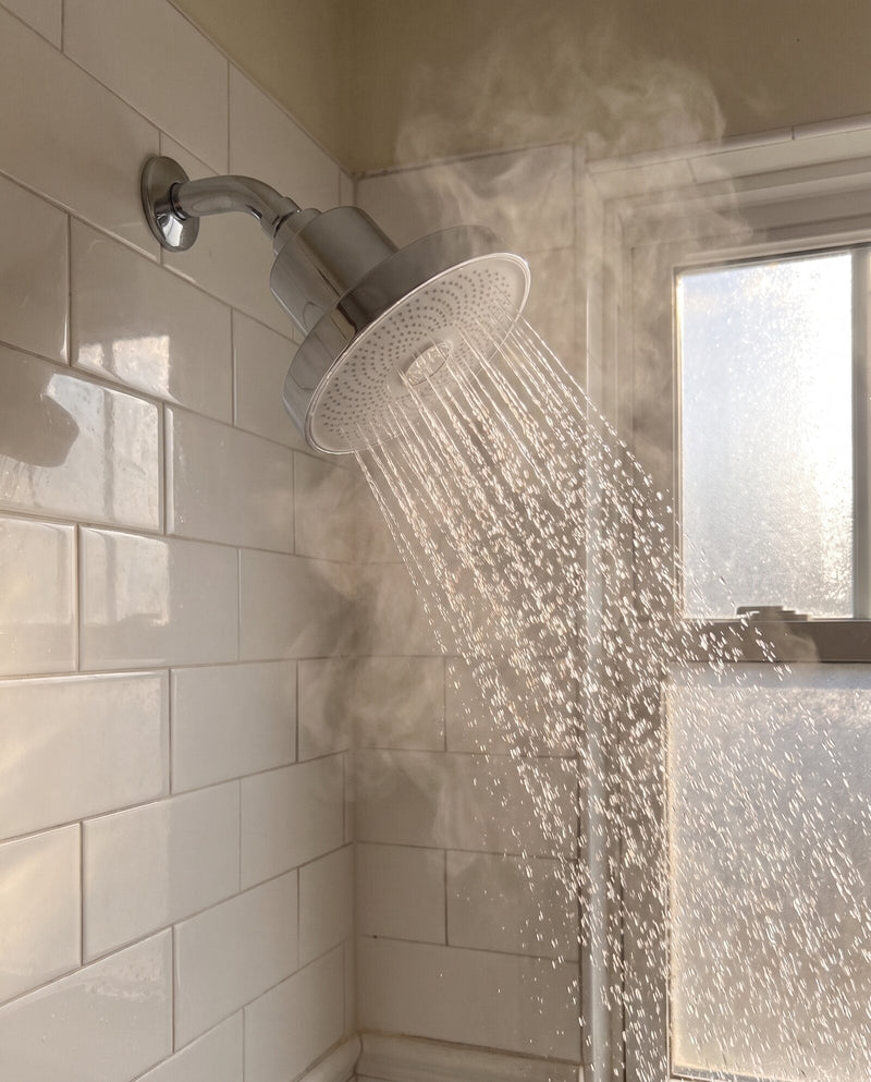 Rinze showerhead running in a white tile shower