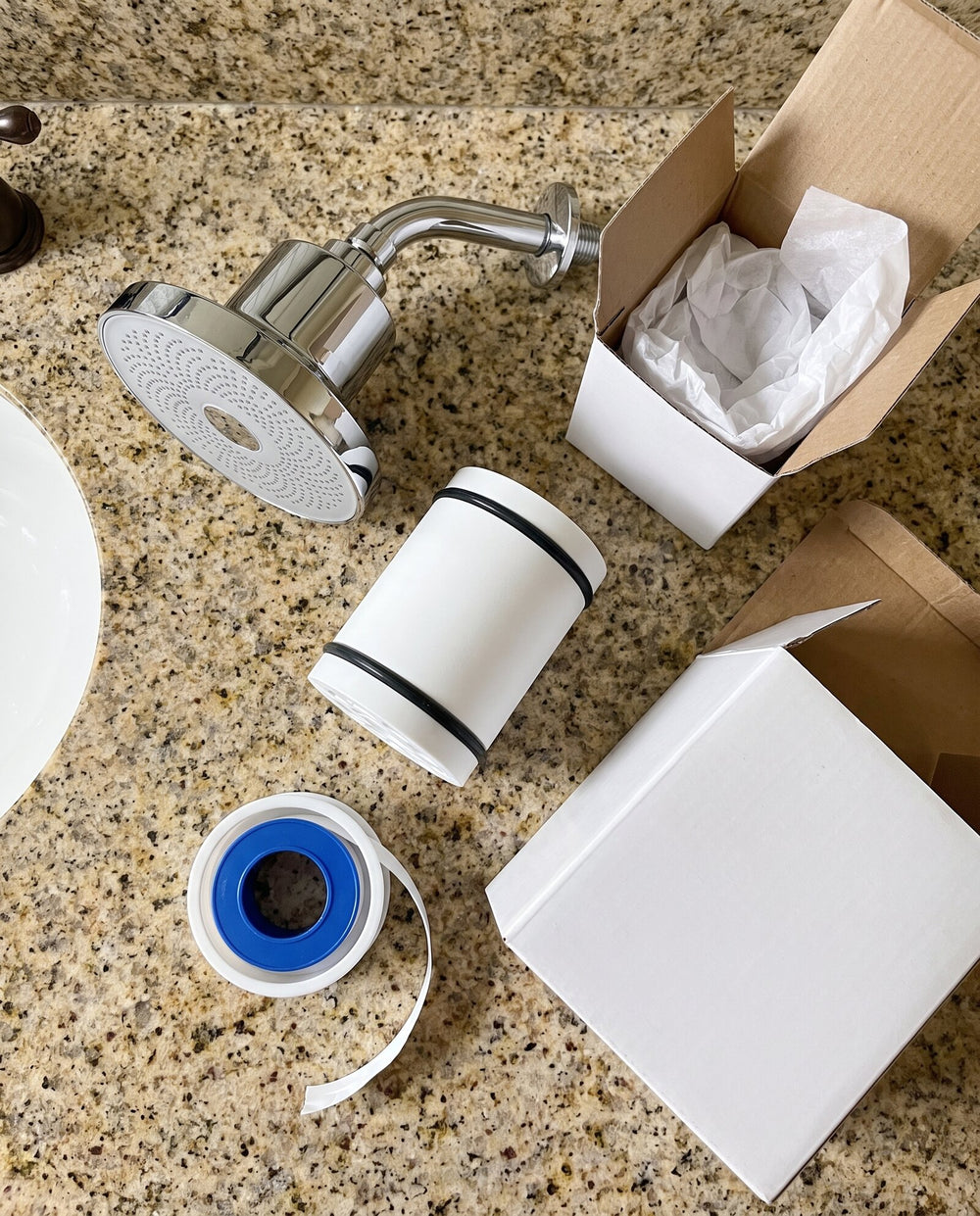 Rinze showerhead, spare cartridge and plumber's tape unboxed on a bathroom counter